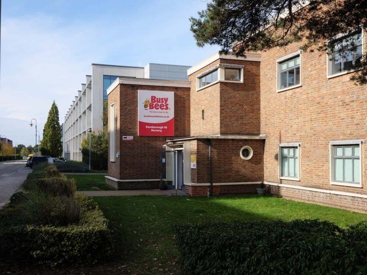 Exterior view of a childcare center with a brick building and a sign reading "Busy Bees"