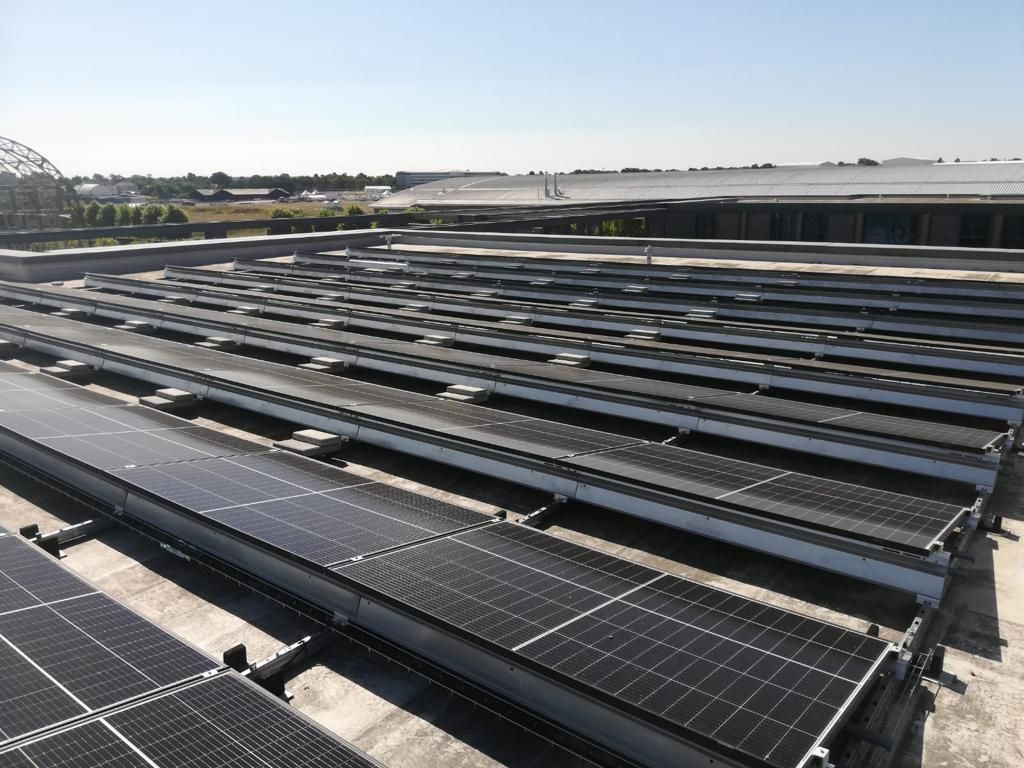Rooftop solar panels atop the office building, under a clear sky, are arranged for sunlight exposure
