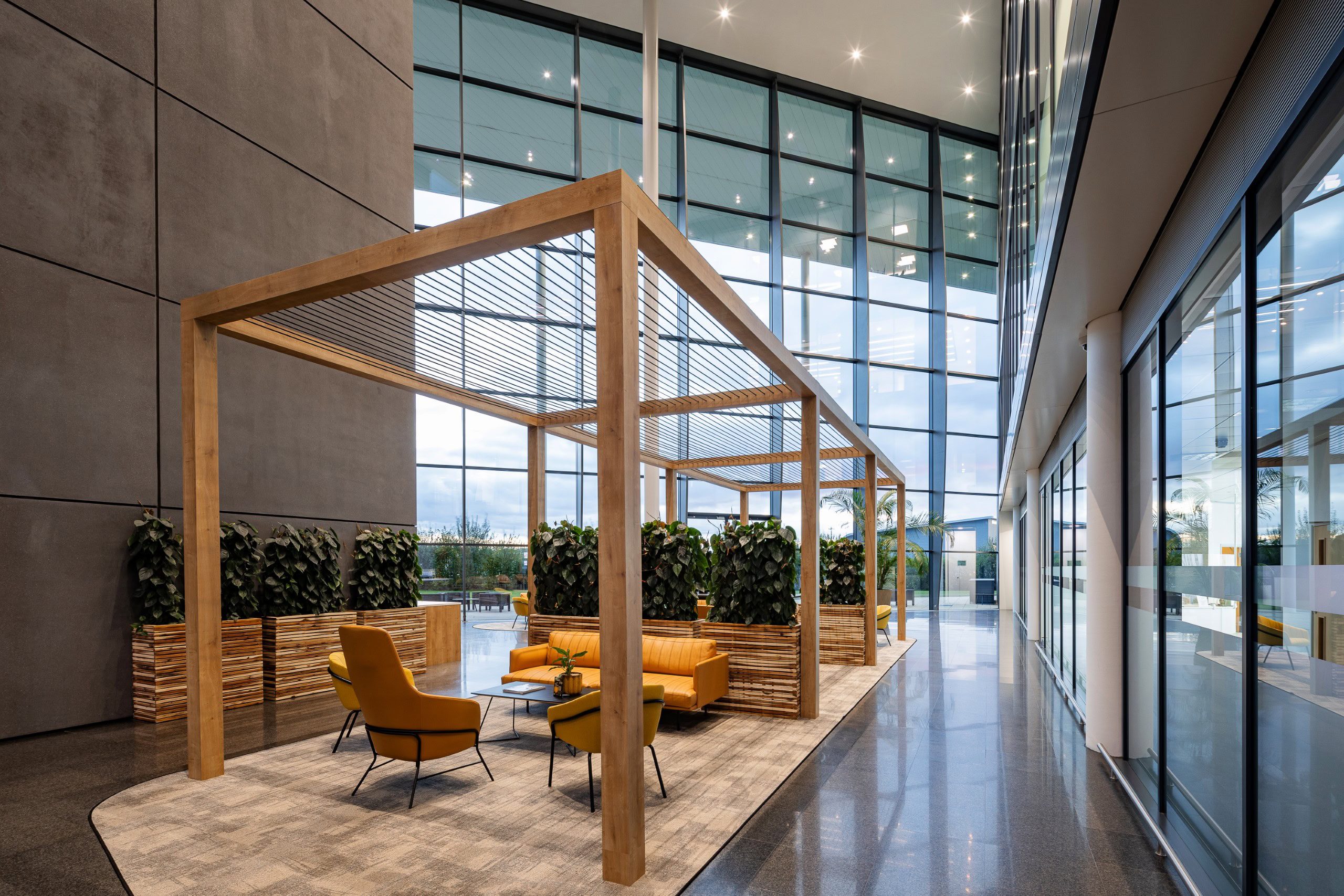 A modern indoor seating area within an office building featuring orange chairs and plants