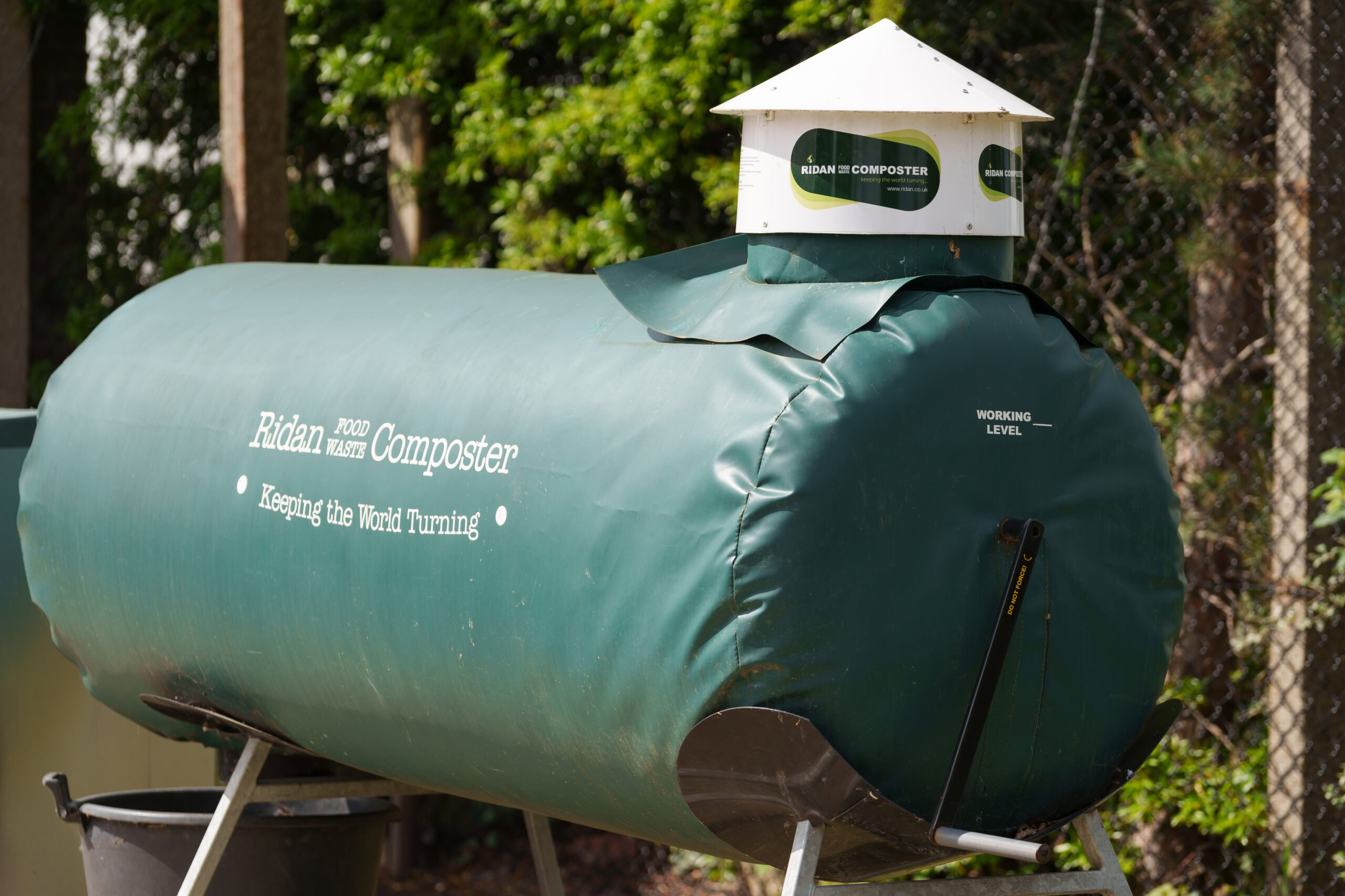 Green Ridan Food Waste Composter with a small roof, labeled "Keeping the World Turning"