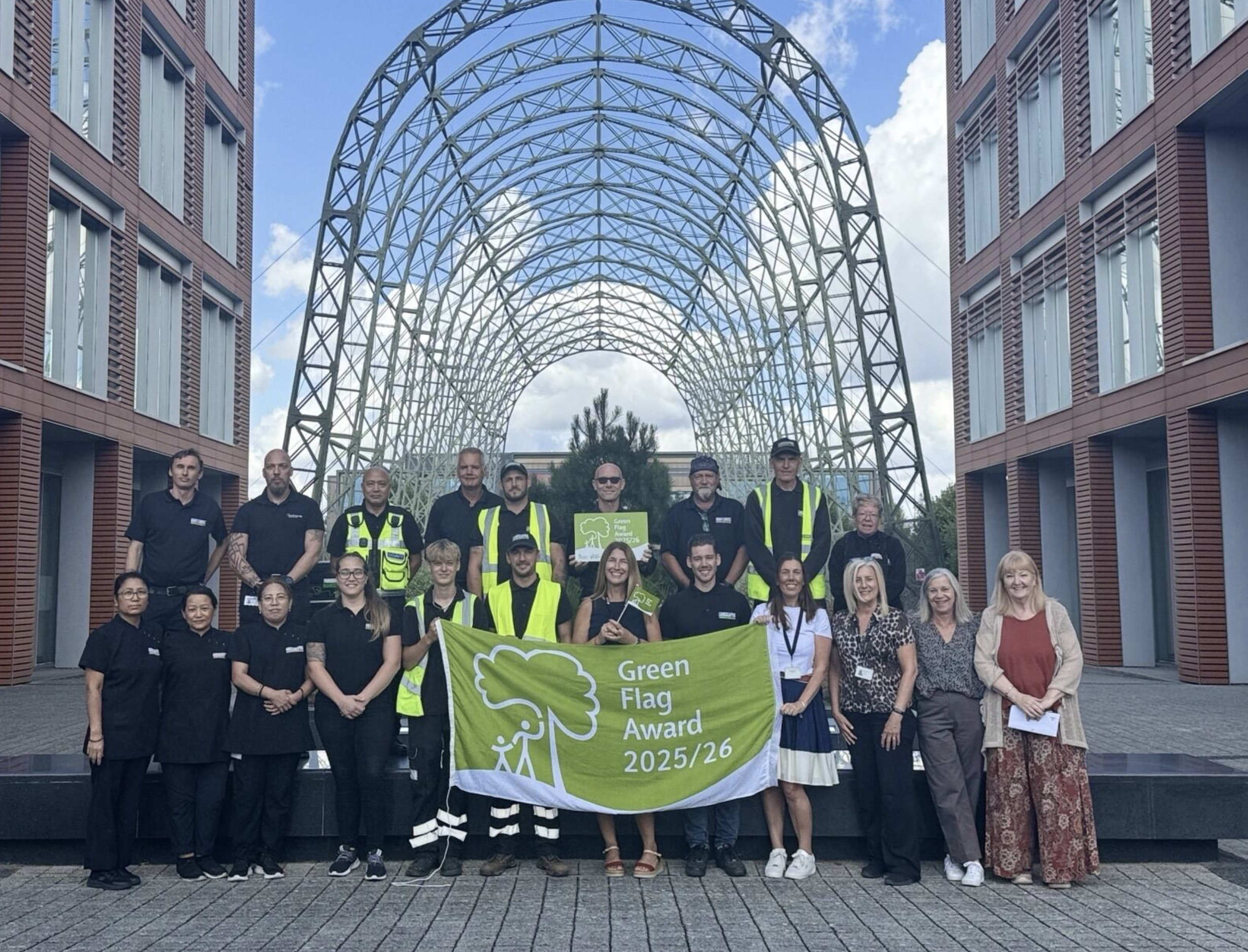 A group of people poses outdoors holding a "Green Flag Award 2025/26" banner.